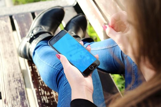 iPhone手机屏幕展示战争雷霆移动版游戏界面，坦克在城市废墟中对战，触控虚拟按键清晰可见